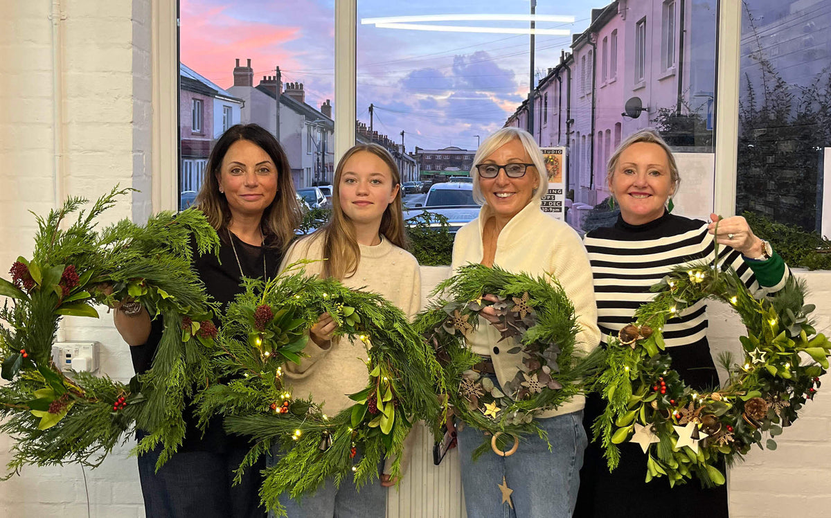 Group holding their finished Christmas wreaths at a wreath making workshop in Hove